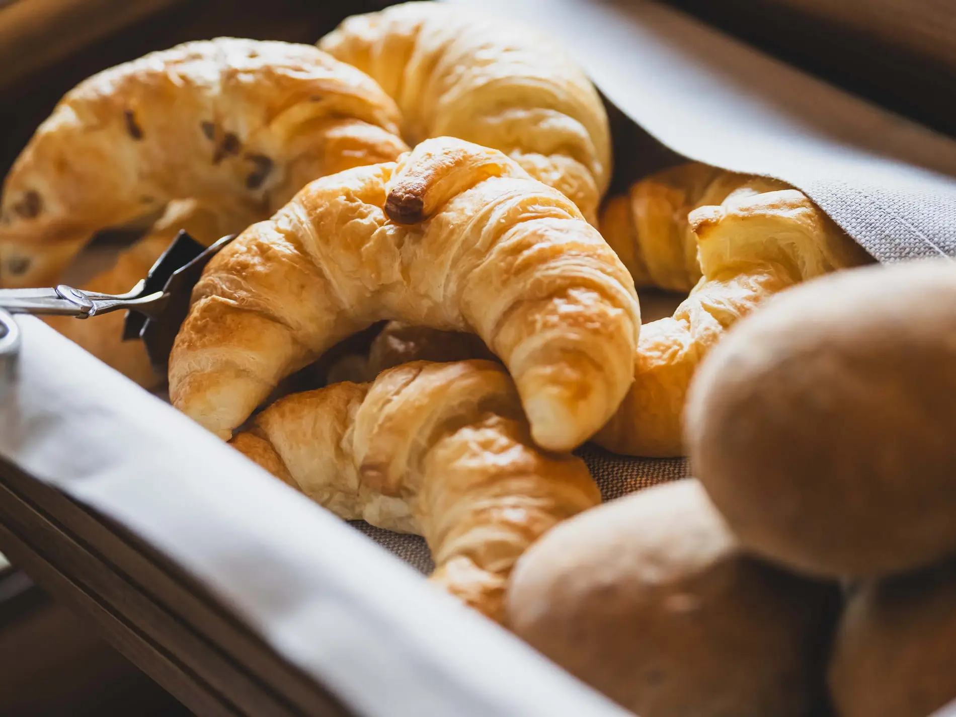 Kulinarische Vielfalt in unseren Restaurants in Brigels Kartoffelkorb mit frischen Croissants und Brötchen