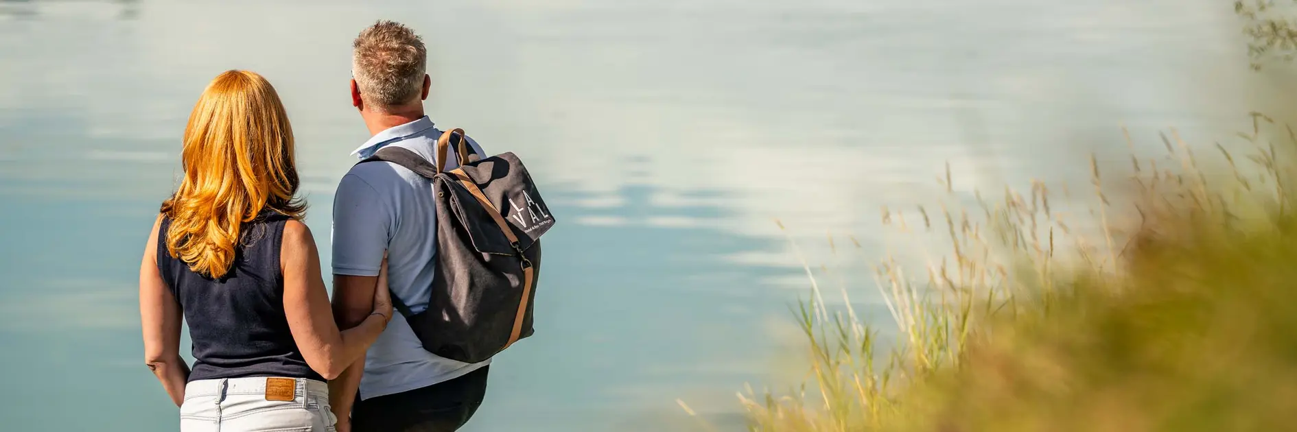 Baden in der Surselva: fünf Wasserplätze für den Sommer Paar steht am Ufer und blickt auf ruhigen See mit Spiegelung
