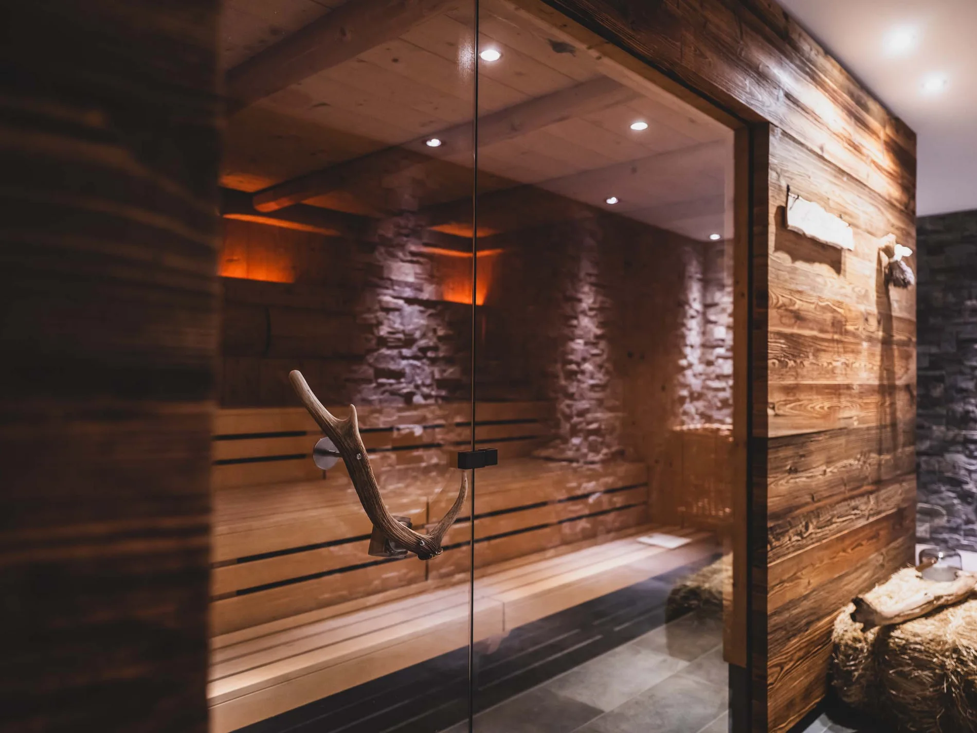 Moderne Sauna mit Holz- und Steindekor und Hirschgeweih als Türgriff