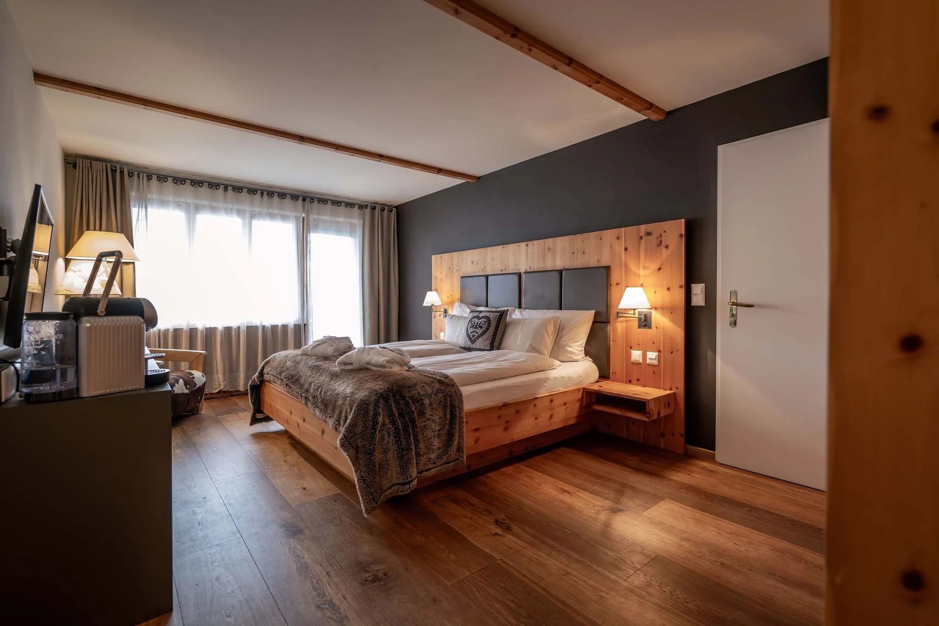 Gemütliches Hotelzimmer mit Holzbett, Fernseher und Tageslicht durch Fenster