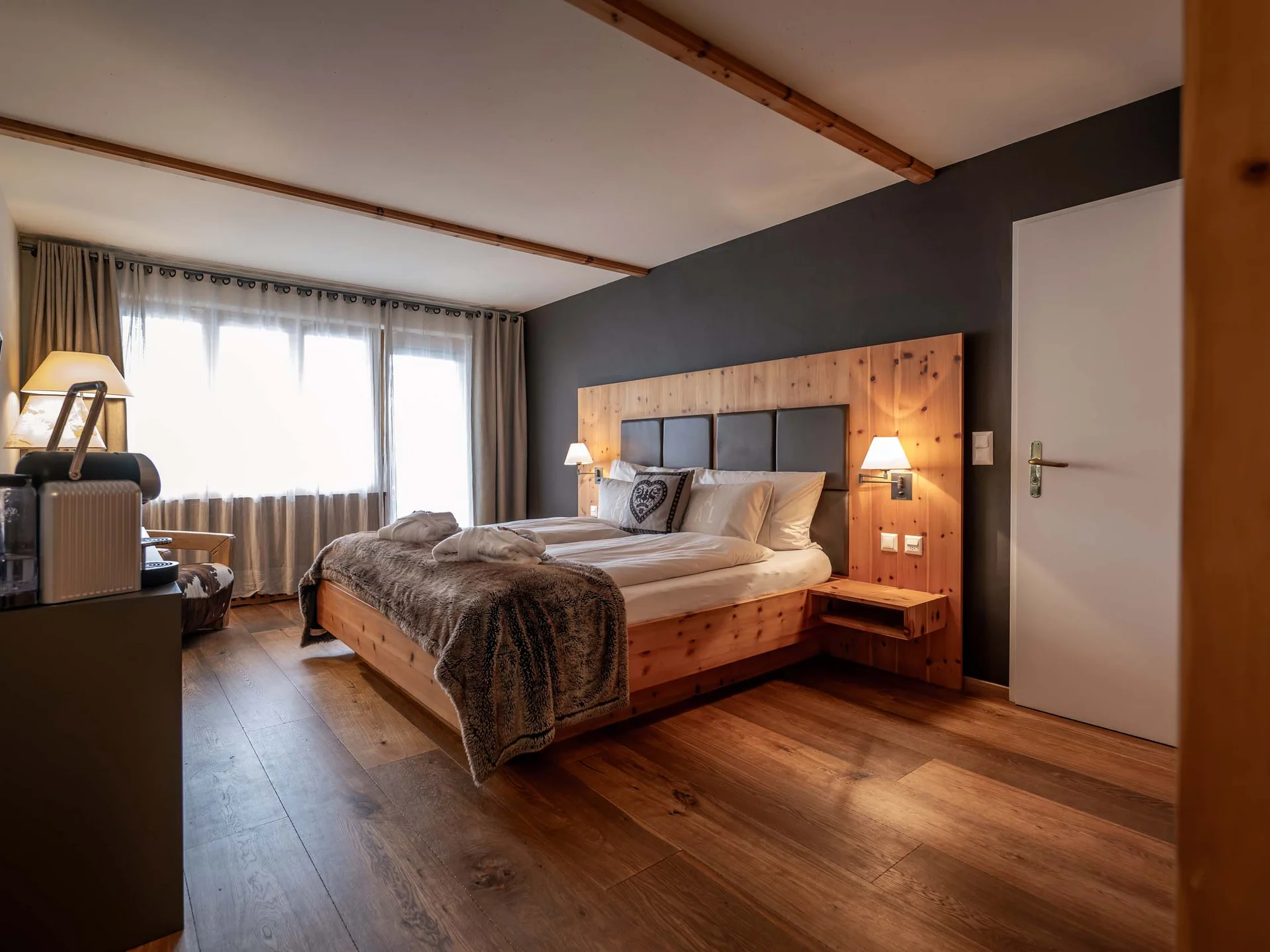 Gemütliches Hotelzimmer mit Holzbett, Fernseher und Tageslicht durch Fenster