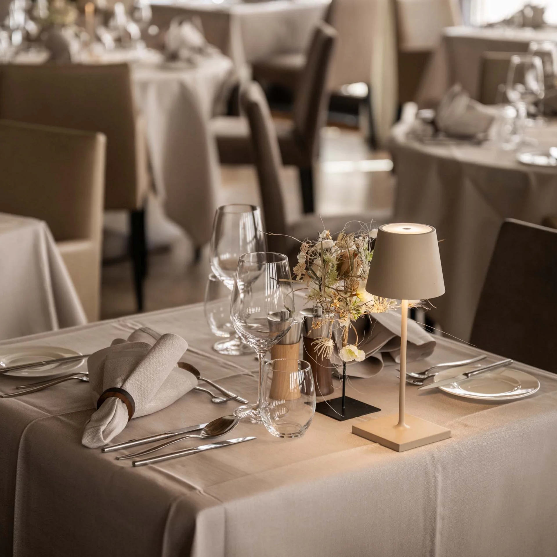 Eleganter Tisch in einem Restaurant mit weißer Tischdecke, Besteck und Lampe