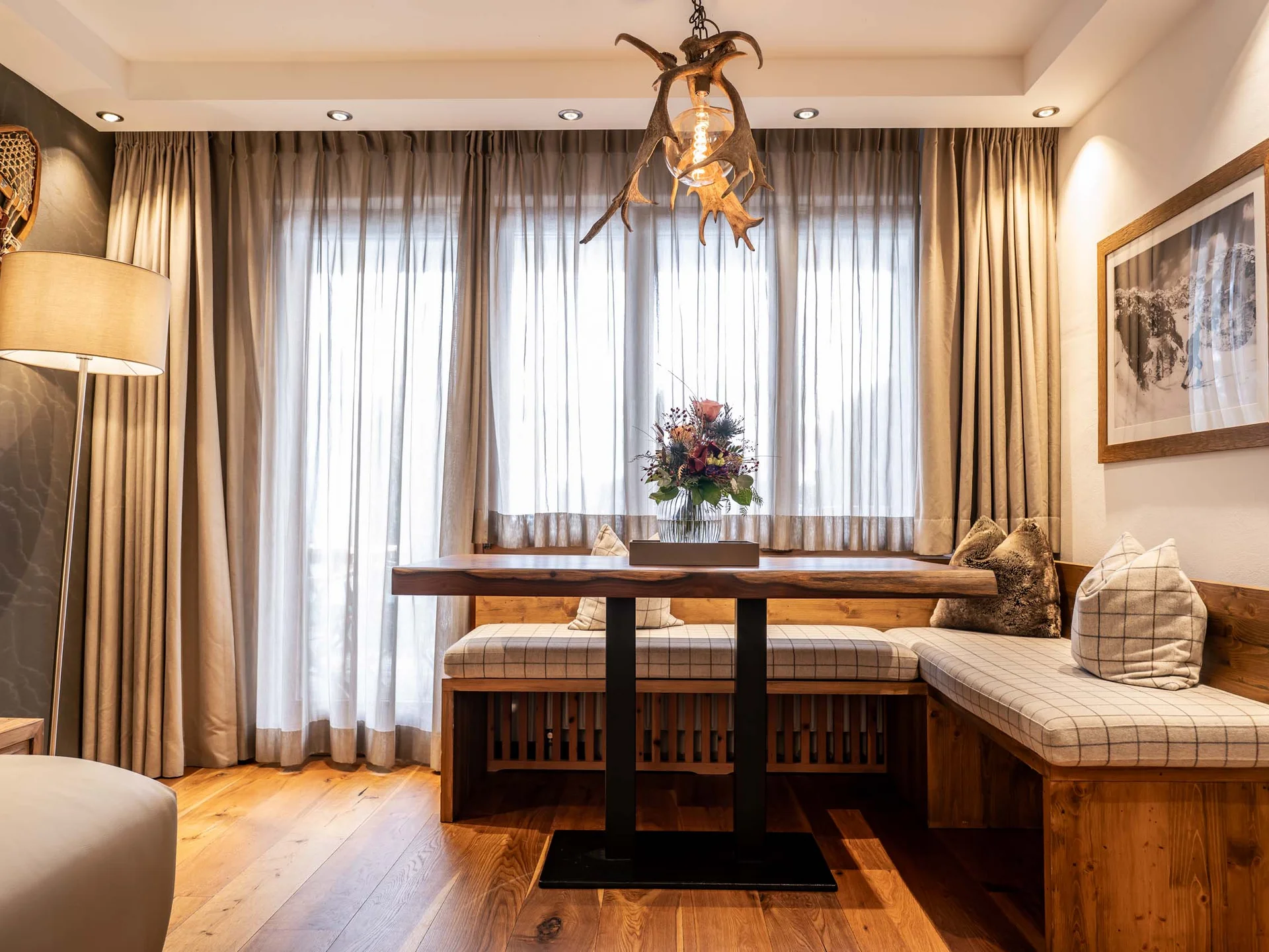 Gemütliche Essecke mit Holztisch, Polstersitzbank und Hirschgeweih-Lampe