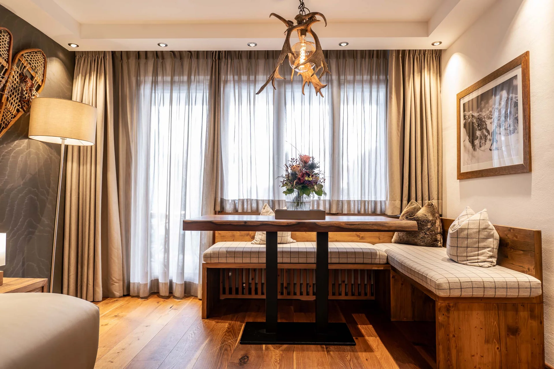 Gemütliche Essecke mit Holztisch, Polstersitzbank und Hirschgeweih-Lampe