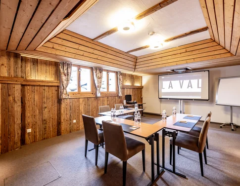 Konferenzraum mit Holzwänden, Stühlen, Tischen und Projektor