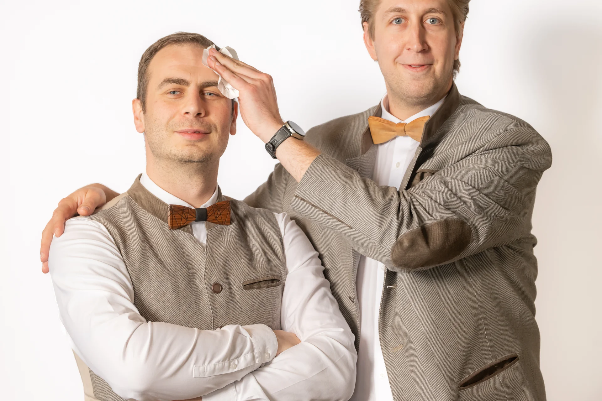 Zwei Männer in traditionellen Anzügen, einer wischt Stirn des anderen ab