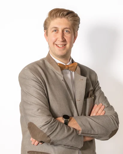 Junger Mann mit grauem Sakko und Fliege vor weißem Hintergrund