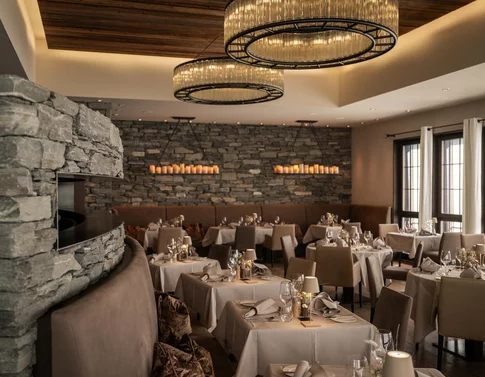 Elegantes Restaurant mit Kamin, Steinwand und gedeckten Tischen