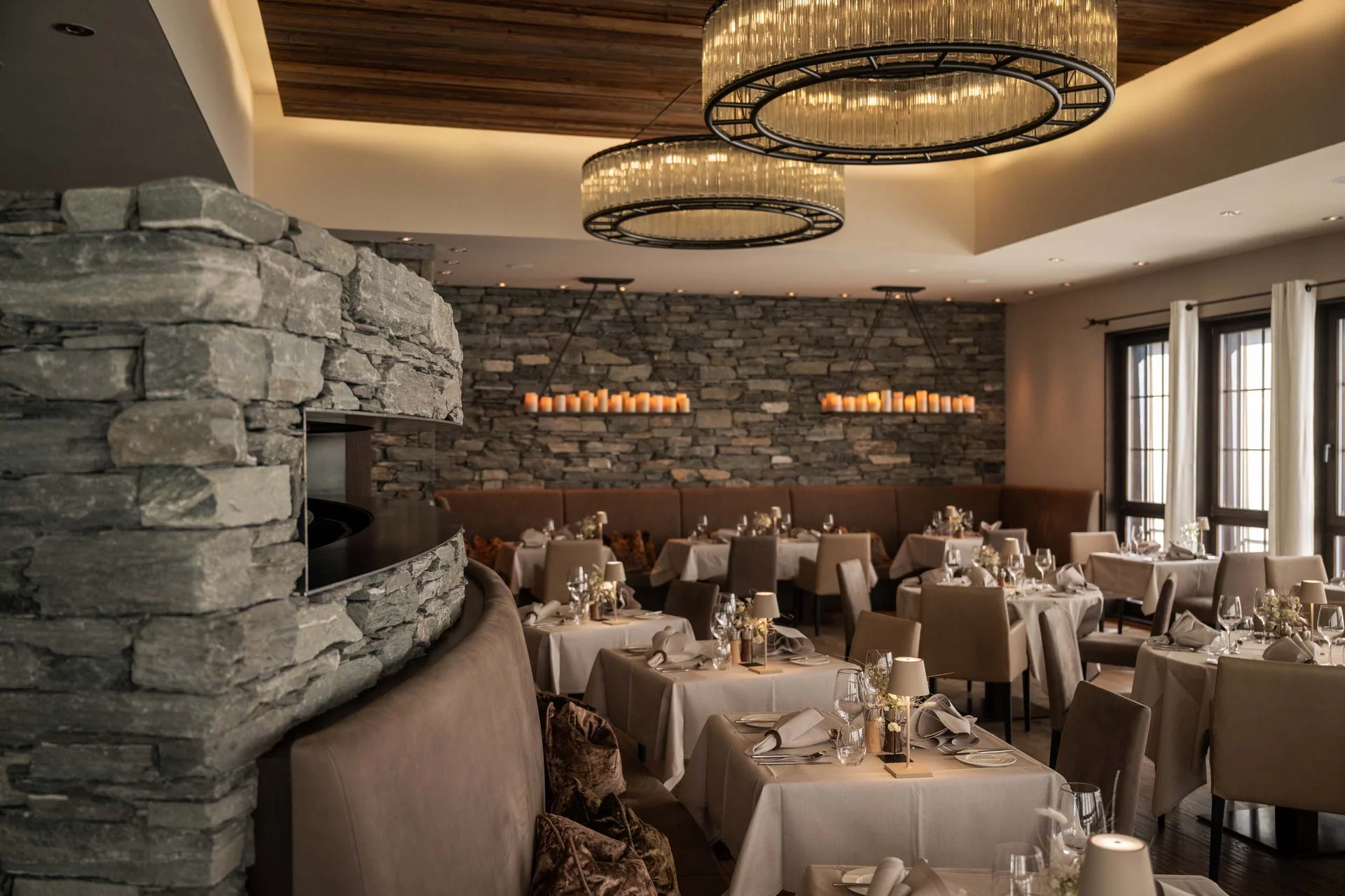 Elegantes Restaurant mit Kamin, Steinwand und gedeckten Tischen