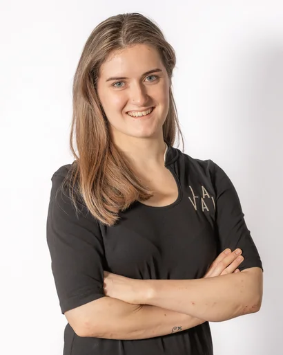 Lächelnde junge Frau mit verschränkten Armen vor weißem Hintergrund