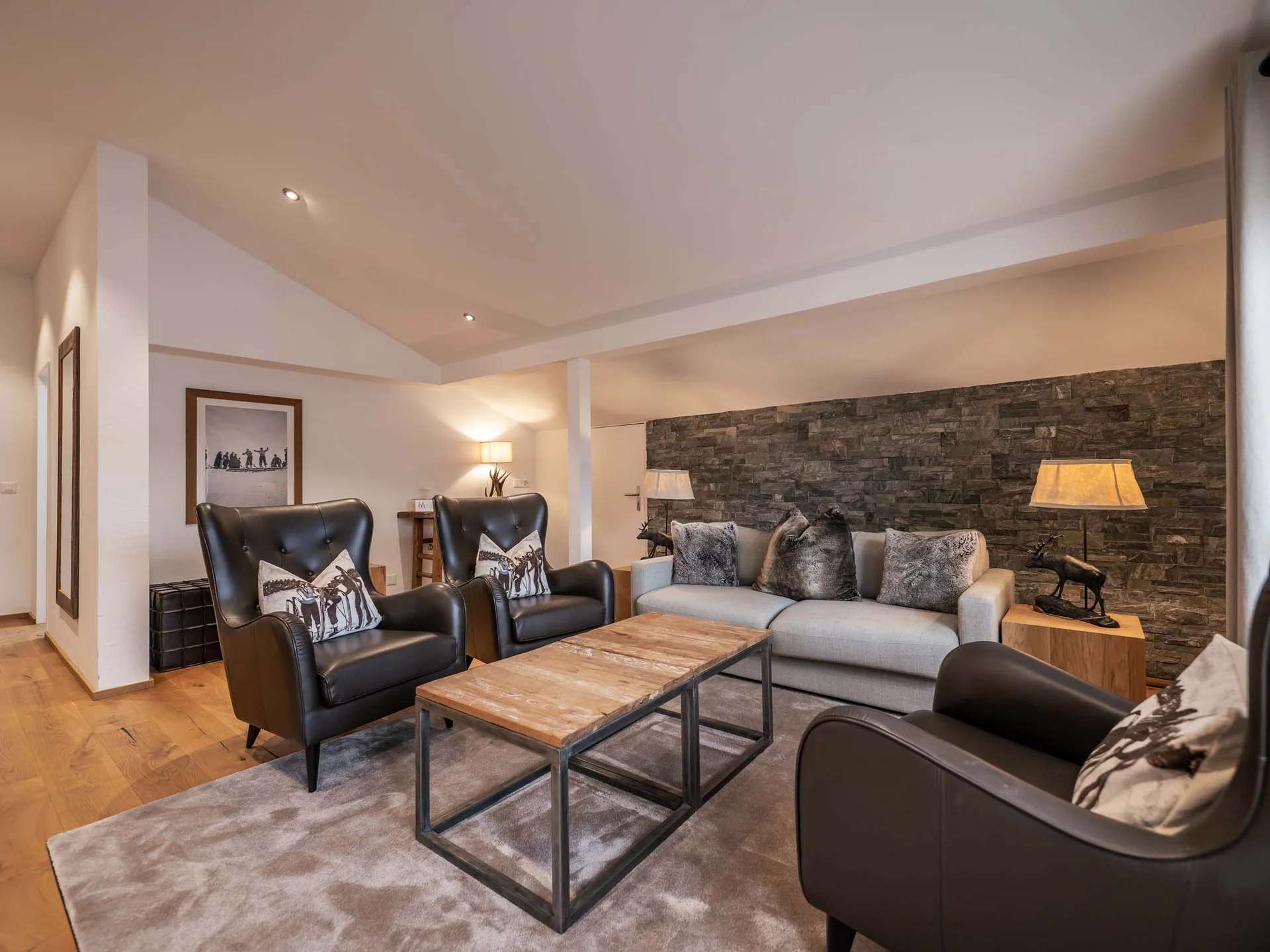 Gemütliches Wohnzimmer mit ledersesseln, sofa und holztisch auf teppich vor steinwand