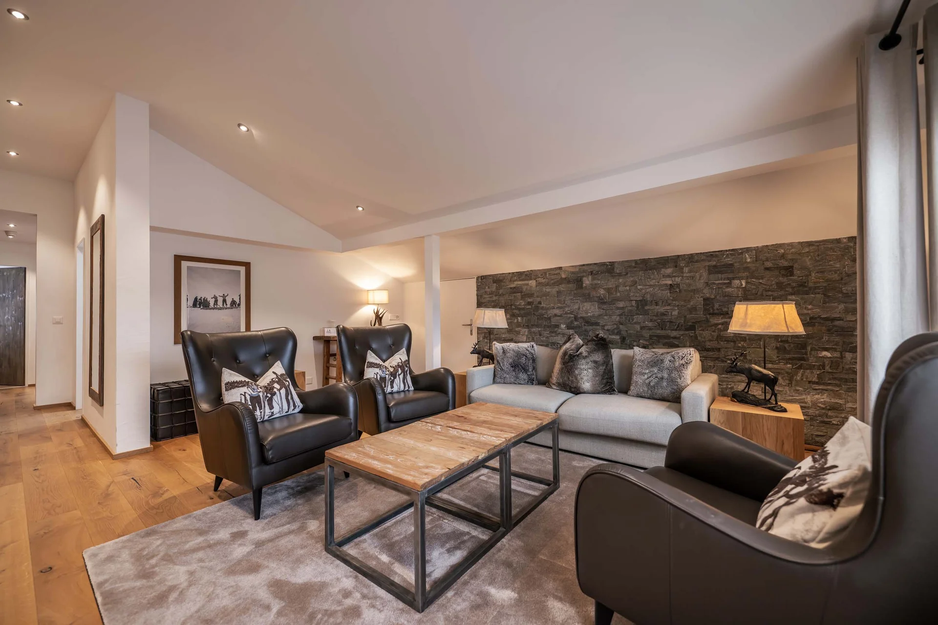 Gemütliches Wohnzimmer mit ledersesseln, sofa und holztisch auf teppich vor steinwand