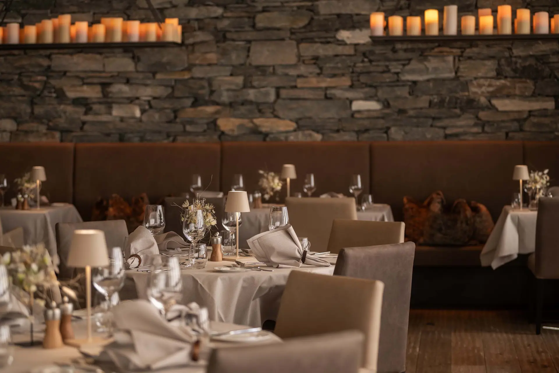 Elegantes Restaurant mit gedeckten Tischen, Kerzen und Steinwand