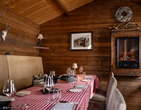 Gemütlicher Essbereich mit kariertem Tisch, Holzwänden und Wandofen