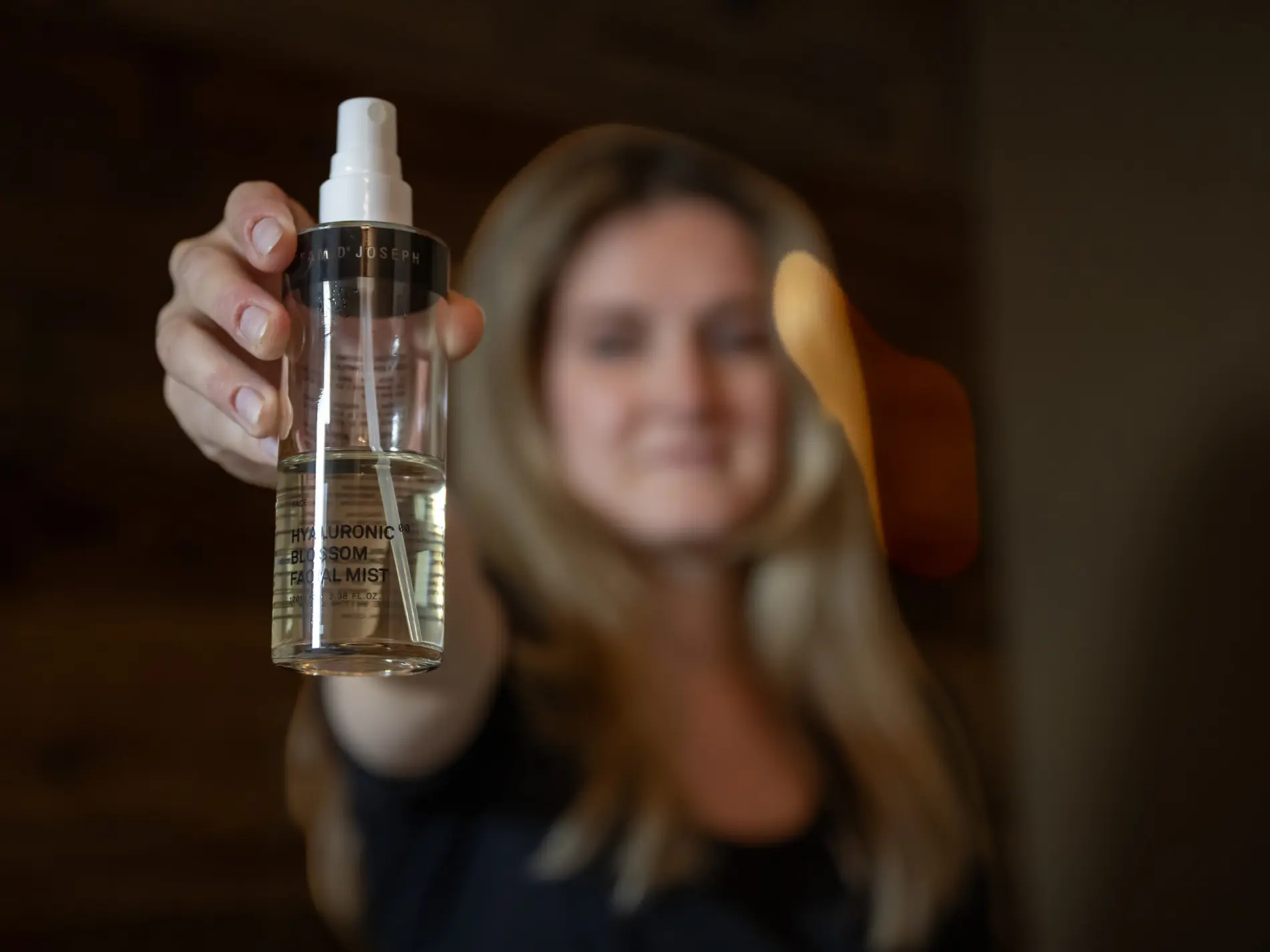 Frau hält eine Flasche mit Hyaluronic Blossom Facial Mist in die Kamera