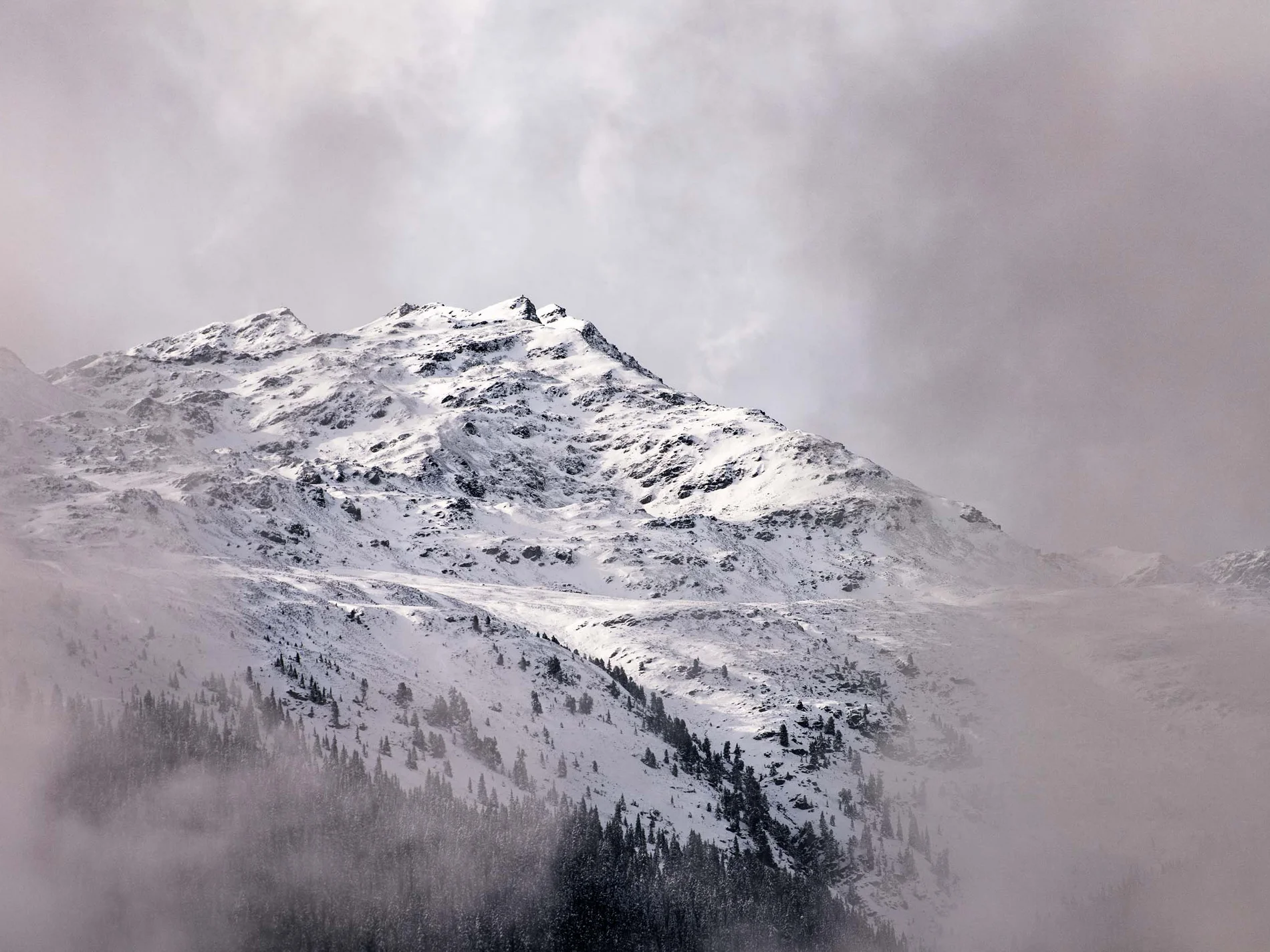 Schneebedeckter Berg mit Nebel und Wolken im Hintergrund