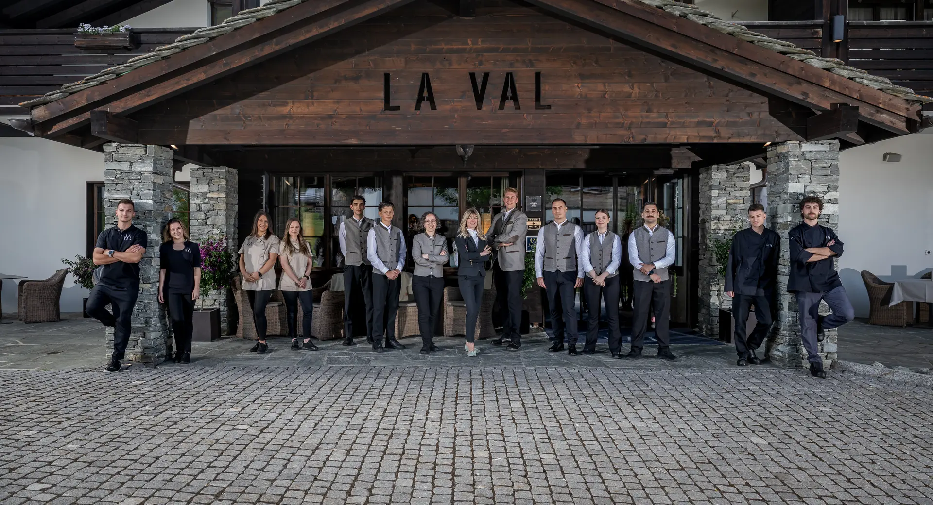 Gastfreundschaft mit Herz für besondere Momente Hotelteam steht vor dem Eingang mit Holzschild La Val