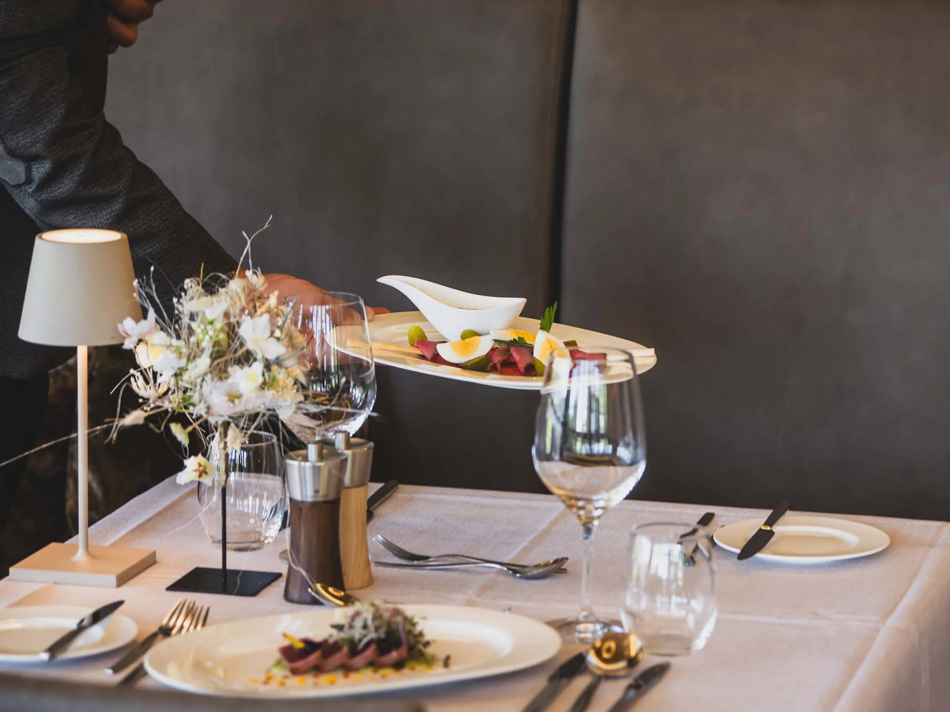 Waiter serving food at a set table in a restaurant