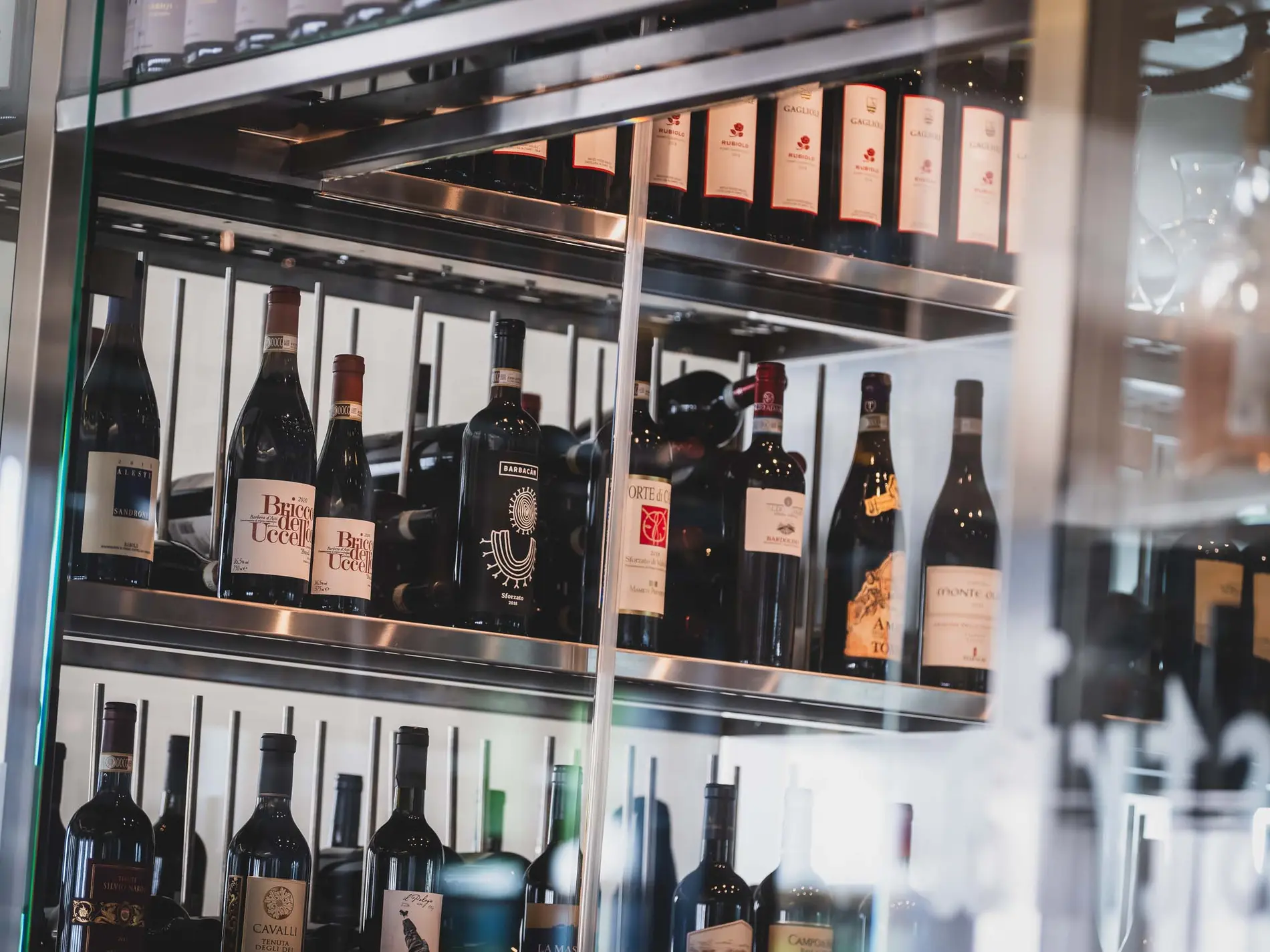 Kulinarische Vielfalt in unseren Restaurants in Brigels Weinflaschen in einem modernen Weinschrank aus Edelstahl und Glas