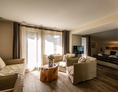 Wohnbereich mit beige Sofas, Holz-Couchtisch und Blick ins Schlafzimmer