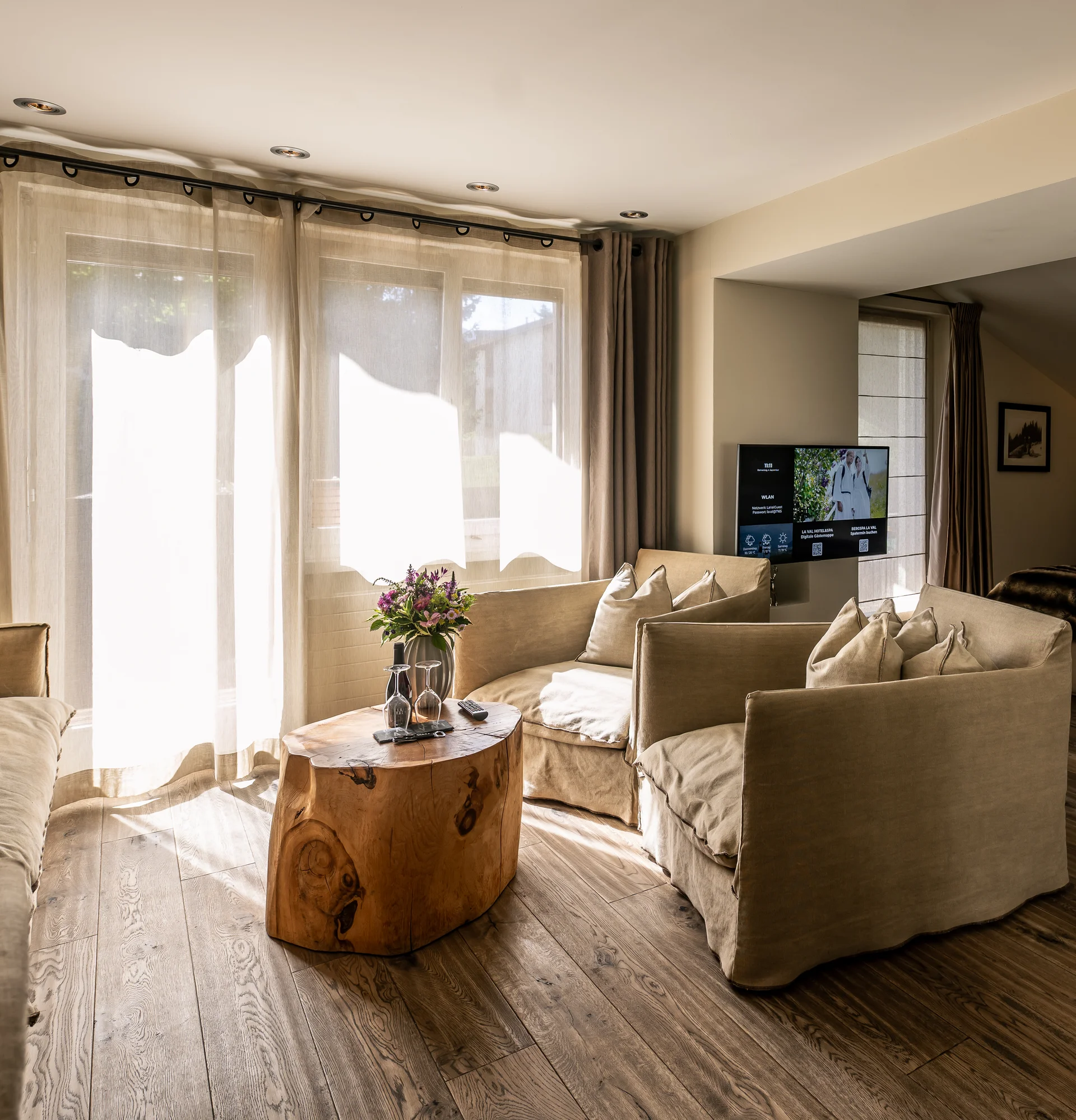 Wohnbereich mit beige Sofas, Holz-Couchtisch und Blick ins Schlafzimmer