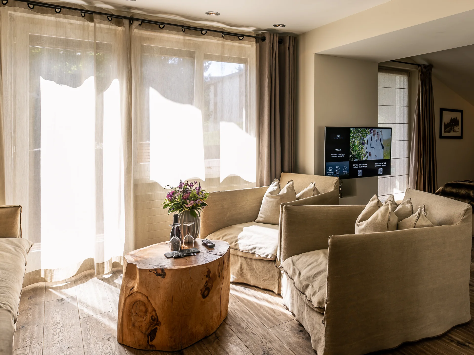 Wohnbereich mit beige Sofas, Holz-Couchtisch und Blick ins Schlafzimmer