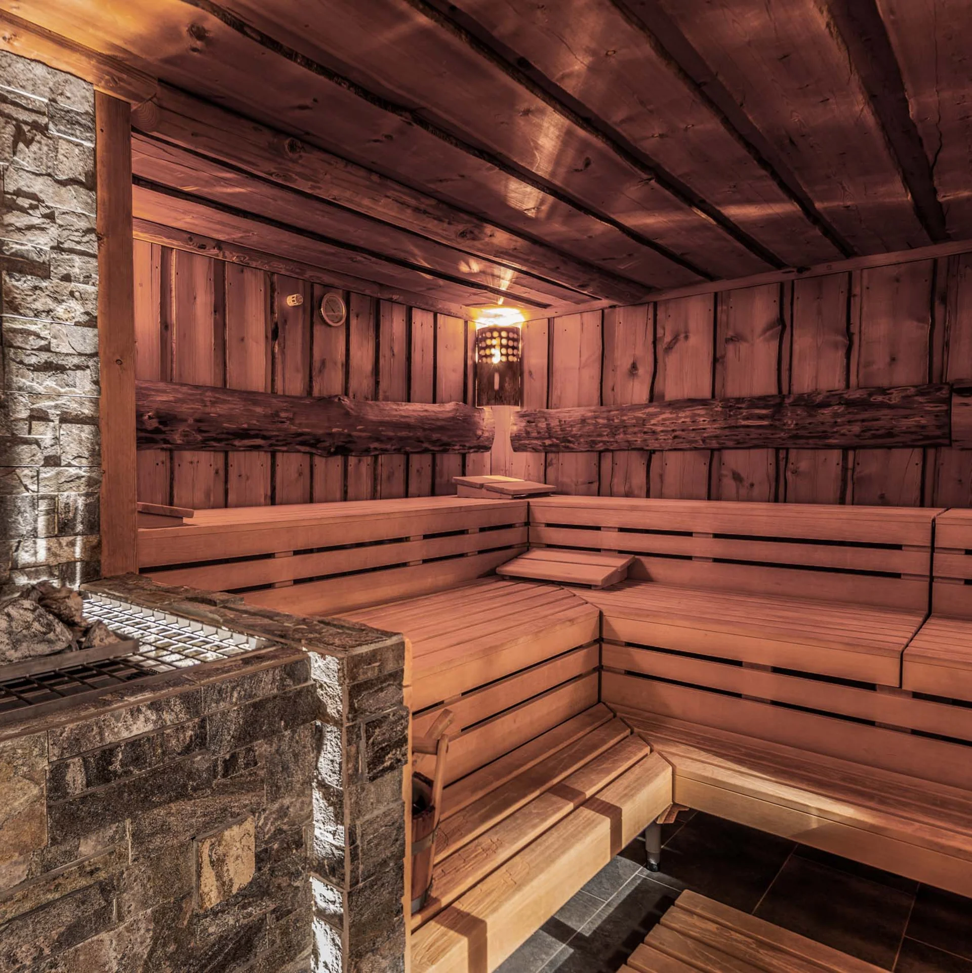 Innenaufnahme einer traditionellen finnischen Sauna mit Holzbänken und Saunaofen