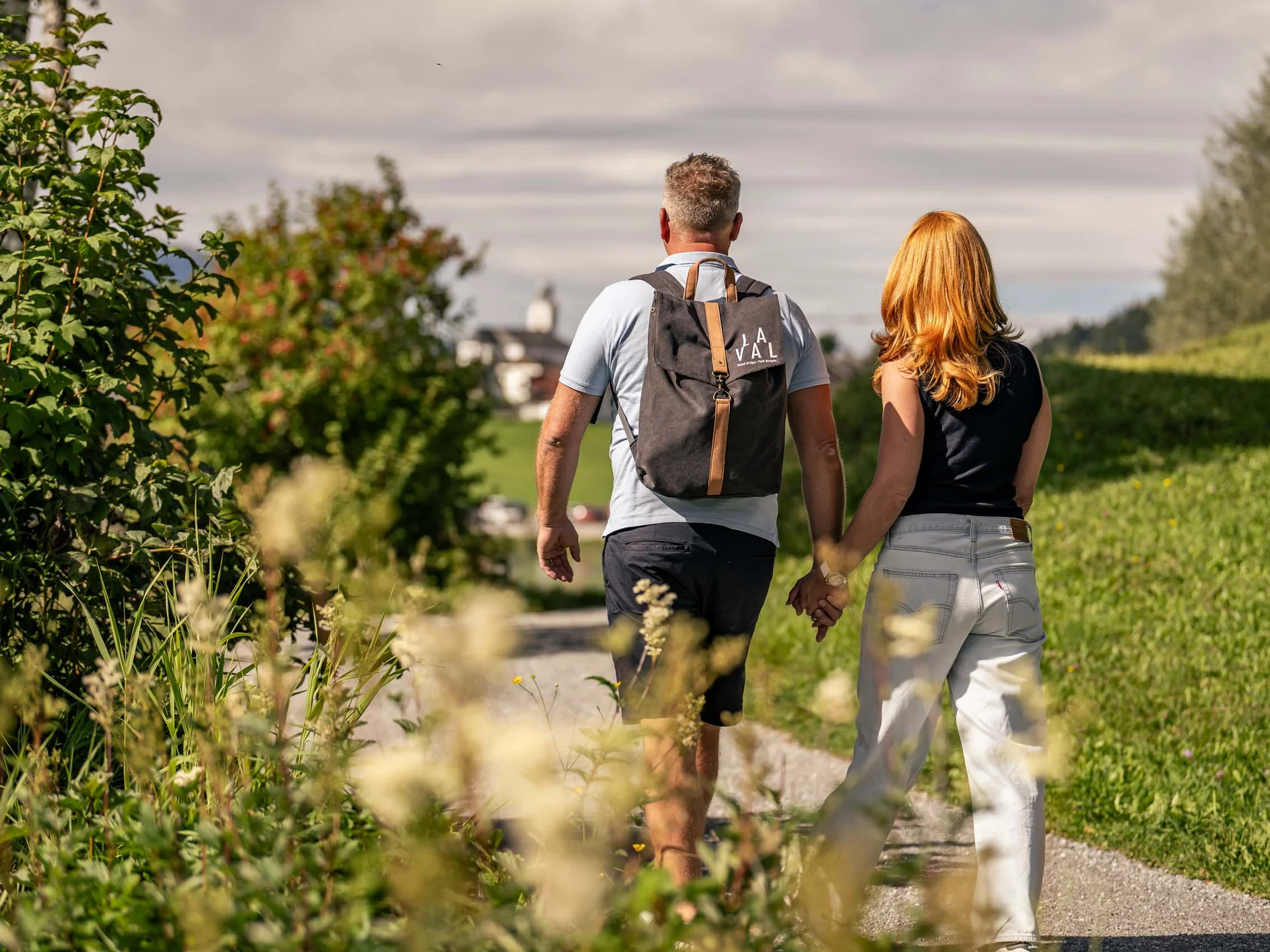 Paar geht Hand in Hand auf einem Weg in grüner ländlicher Umgebung
