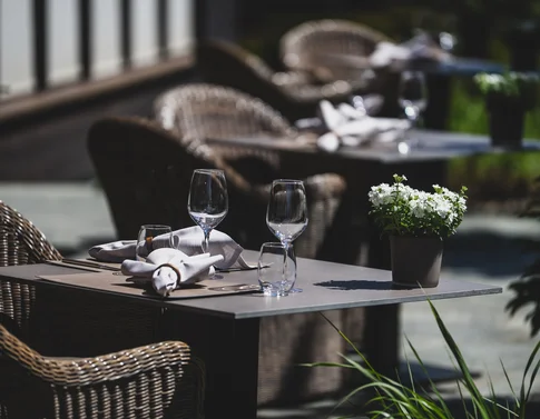 Eingerichteter Außentisch mit Glaswaren, Besteck und Blumentopf