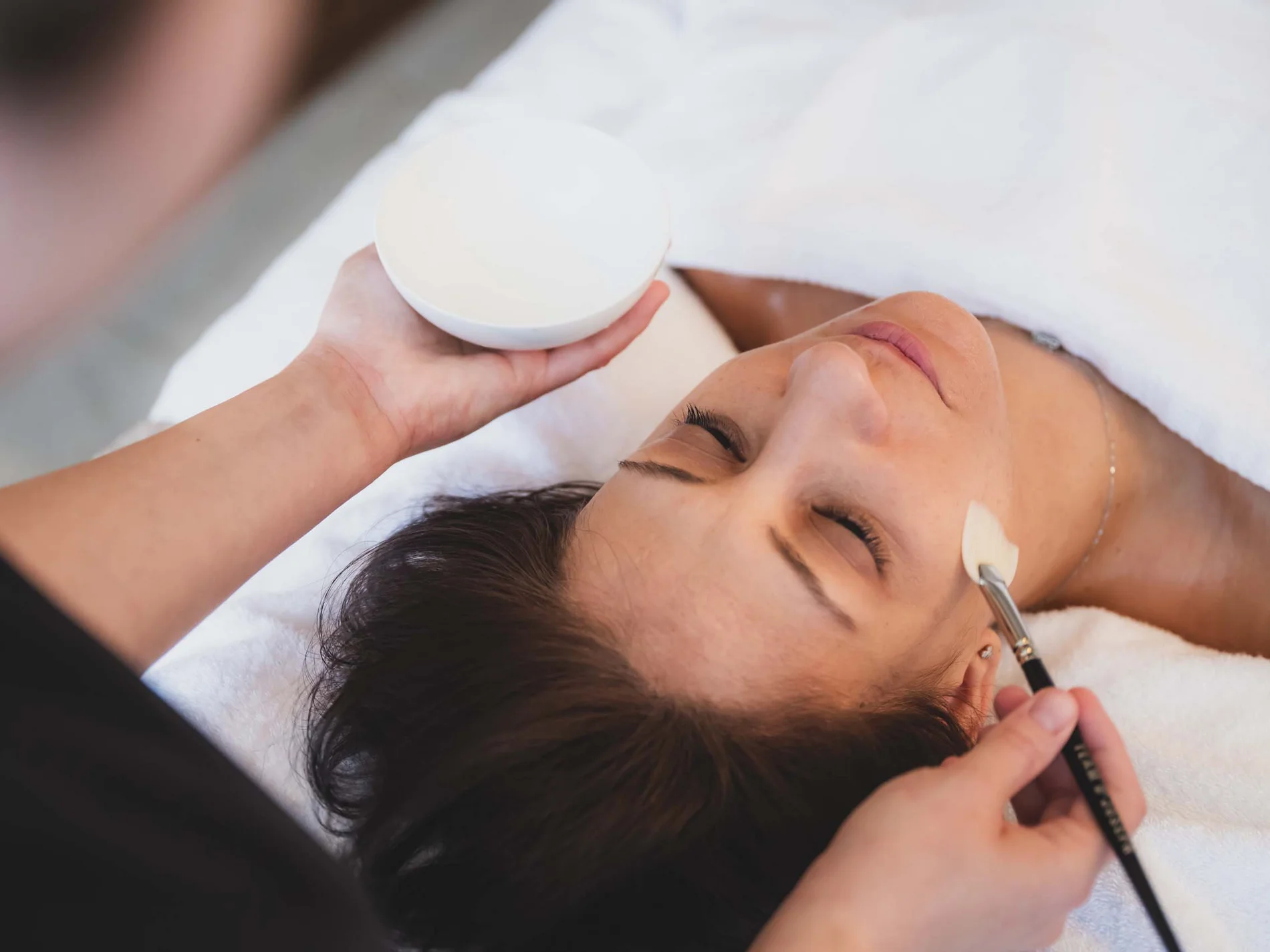 Frau erhält eine Gesichtsbehandlung mit Creme im Spa