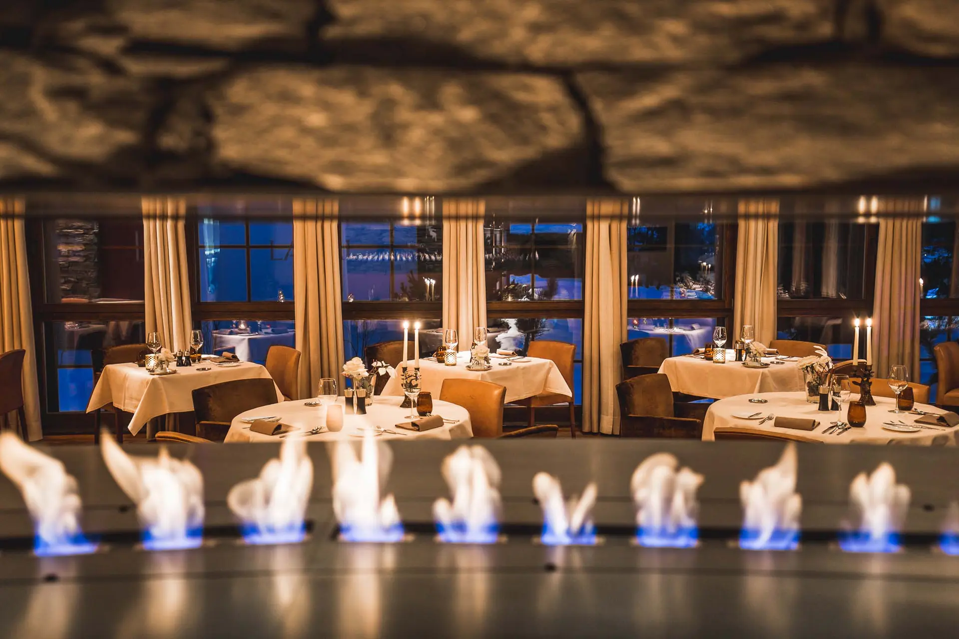 Elegantes Restaurant mit brennendem Kamin und gedeckten Tischen