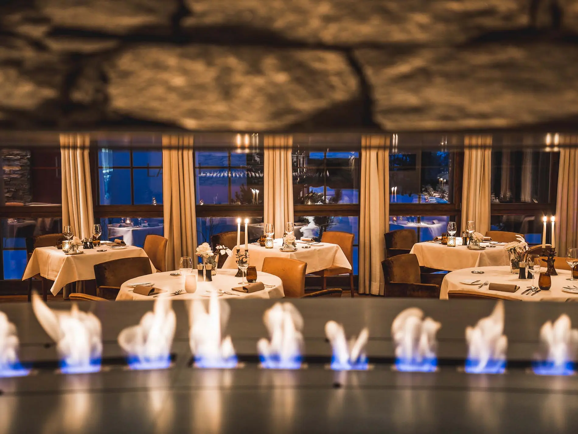 Kulinarische Vielfalt in unseren Restaurants in Brigels Elegantes Restaurant mit brennendem Kamin und gedeckten Tischen