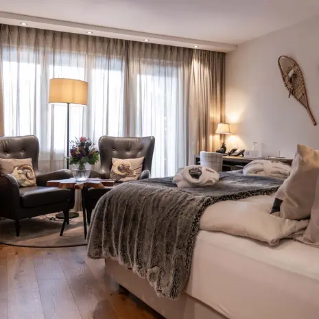 Cozy hotel room with double bed, two armchairs, and wall decorations