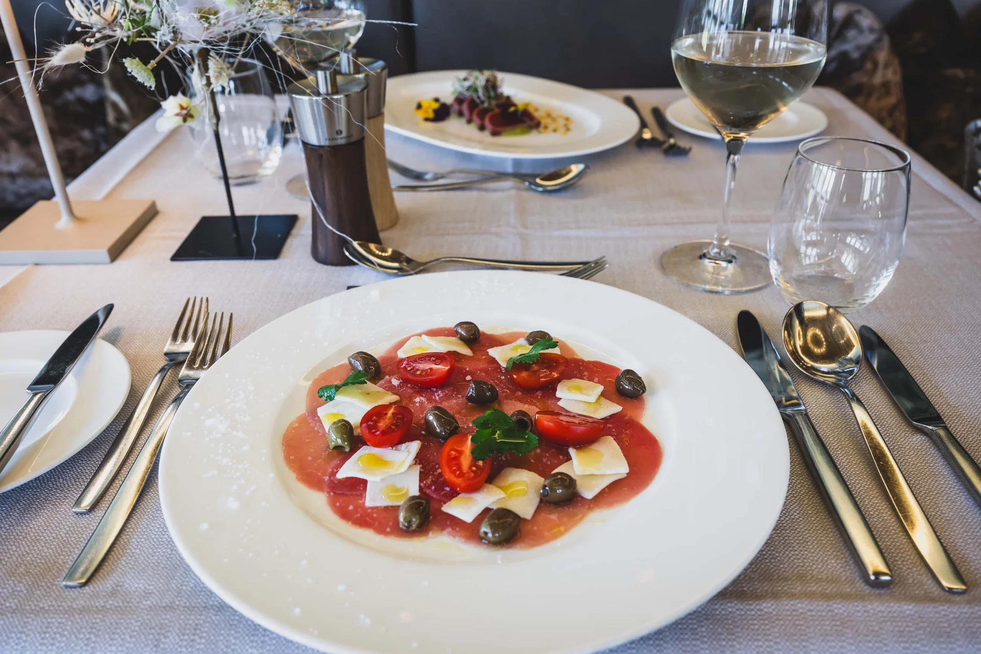 Elegantes Tischgedeck mit einer Vorspeise aus Tomaten, Oliven und Käse
