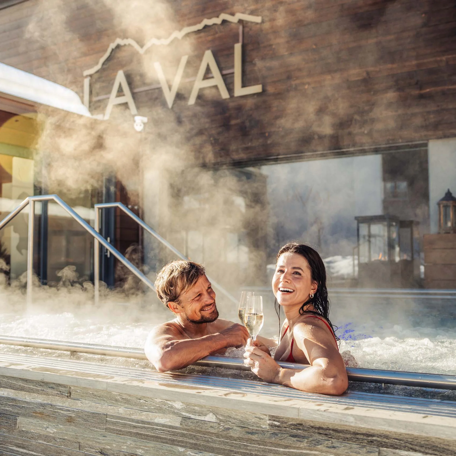 Paar genießt Champagner in Außenwhirlpool mit Dampf im Spa-Resort