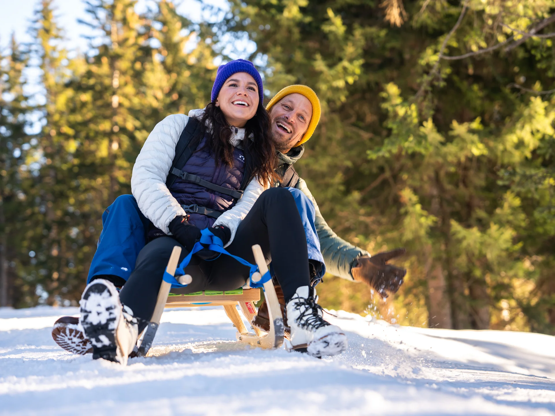 Fröhliches Paar fährt im Schneewald Schlitten im Winter