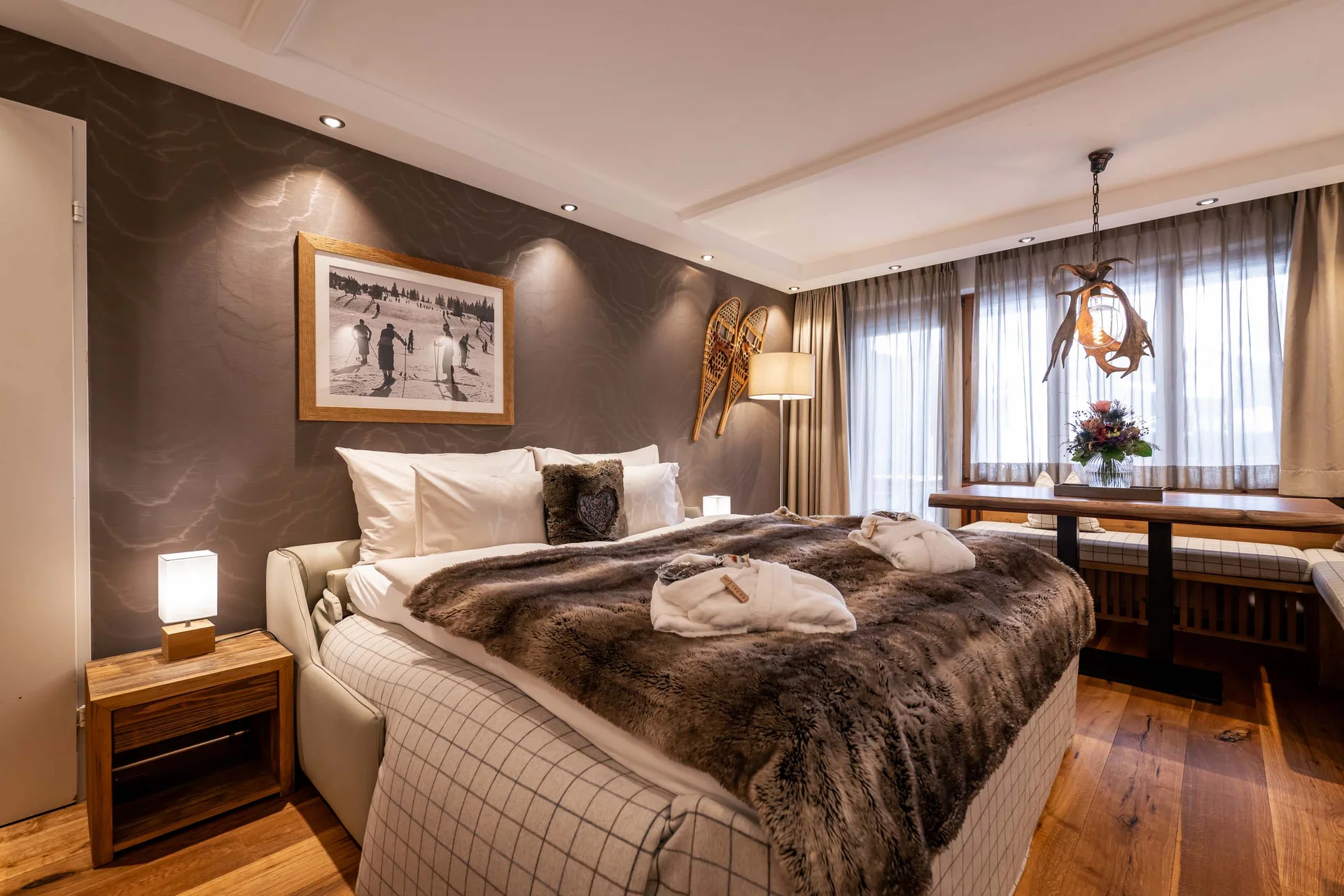 Gemütliches Schlafzimmer mit Fellbettdecke, Schneeschuhen an der Wand und Holzboden