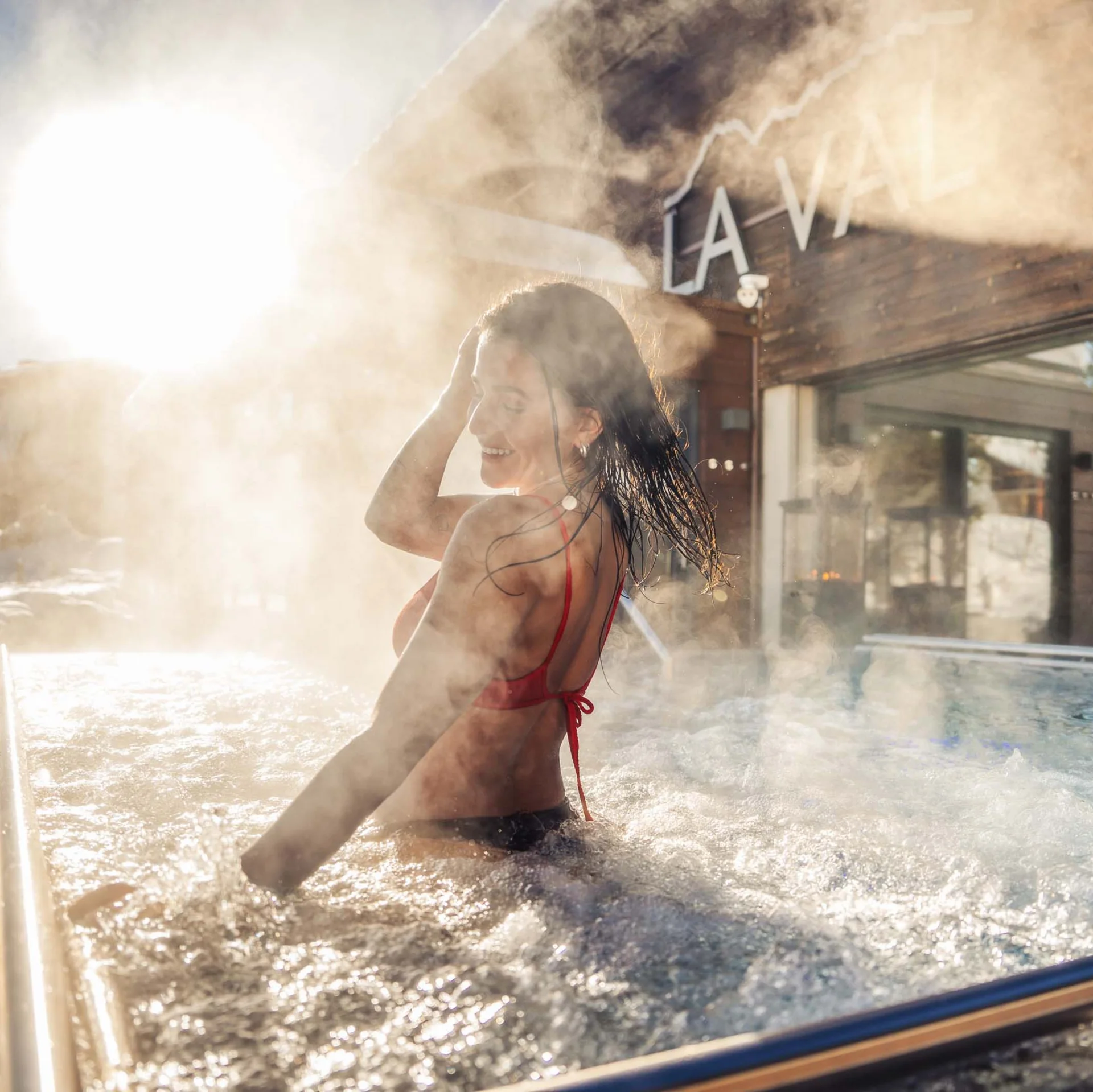 Frau entspannt im dampfenden Außenwhirlpool bei Sonnenschein