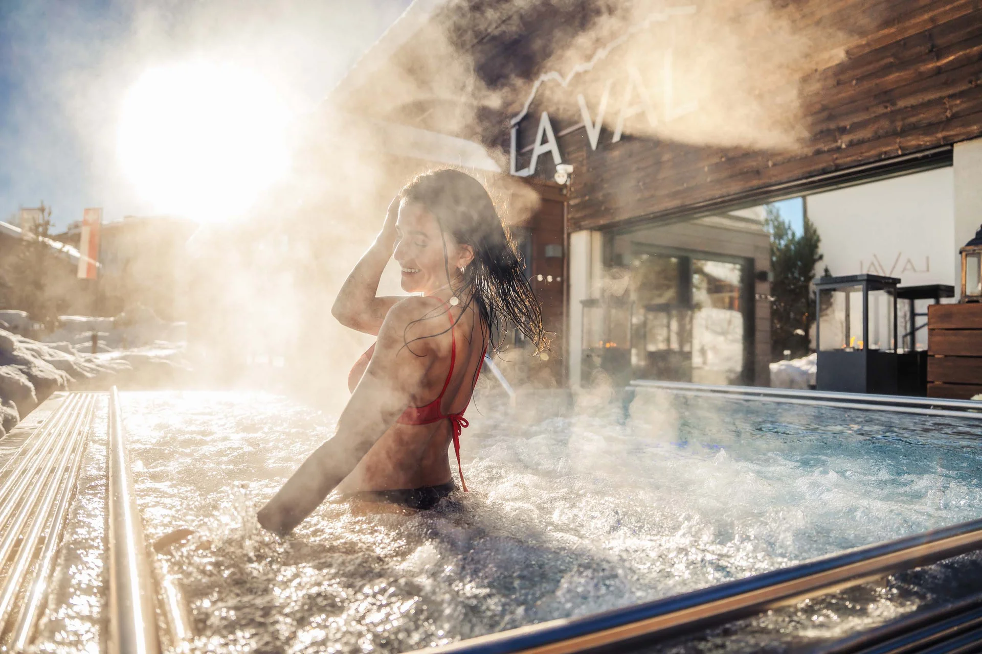 Frau entspannt im dampfenden Außenwhirlpool bei Sonnenschein