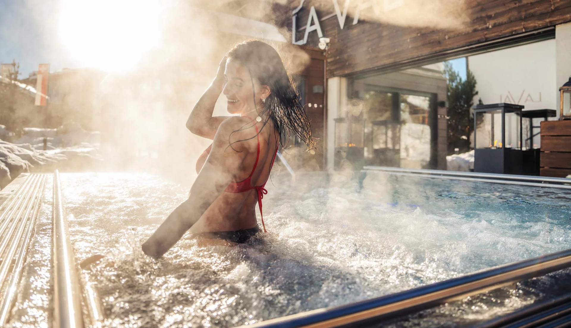 Frau entspannt im dampfenden Außenwhirlpool bei Sonnenschein