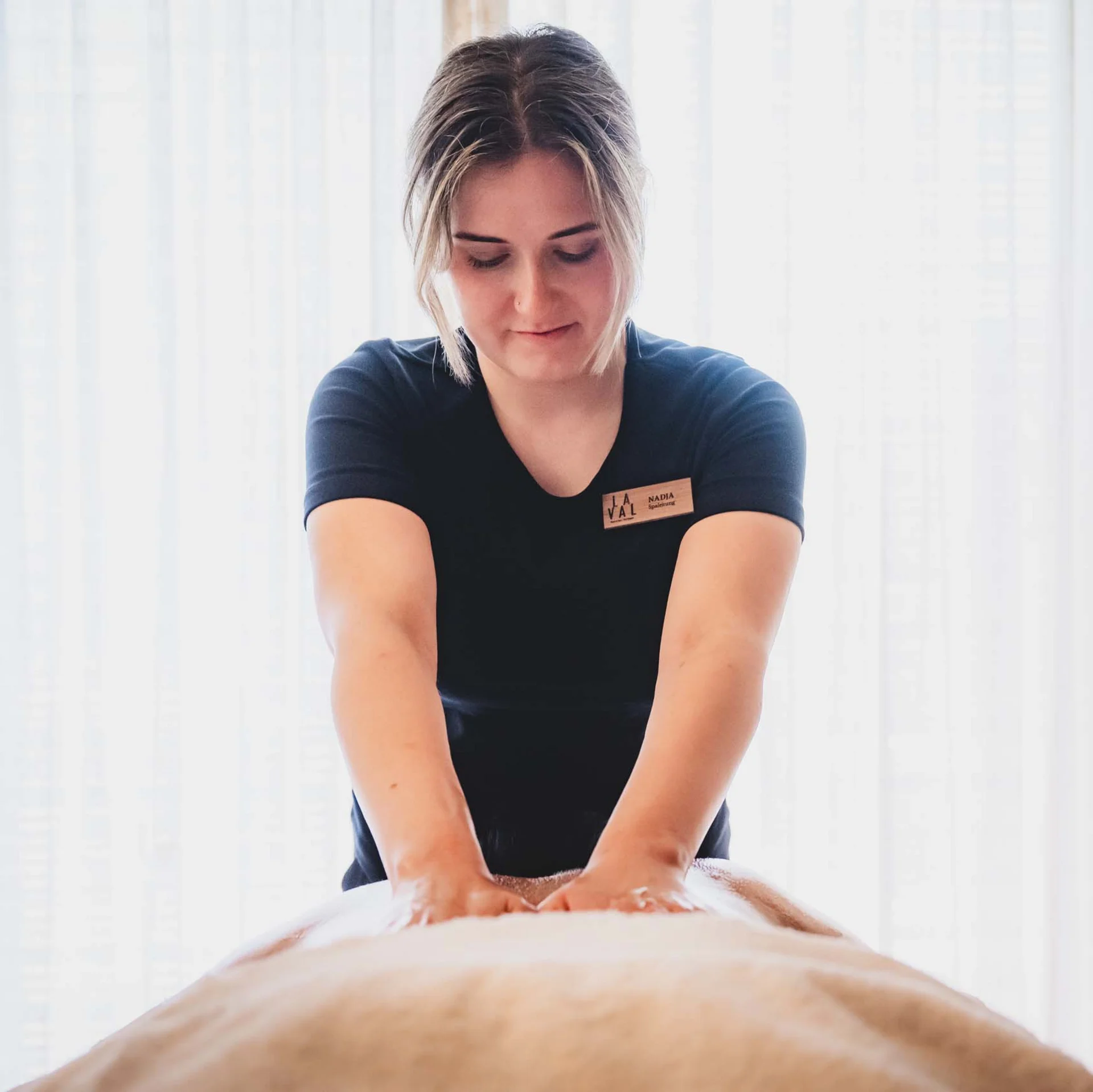 Frau gibt Rückenmassage in hellem Raum