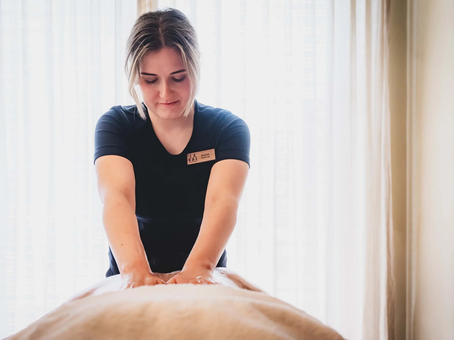 Frau gibt Rückenmassage in hellem Raum