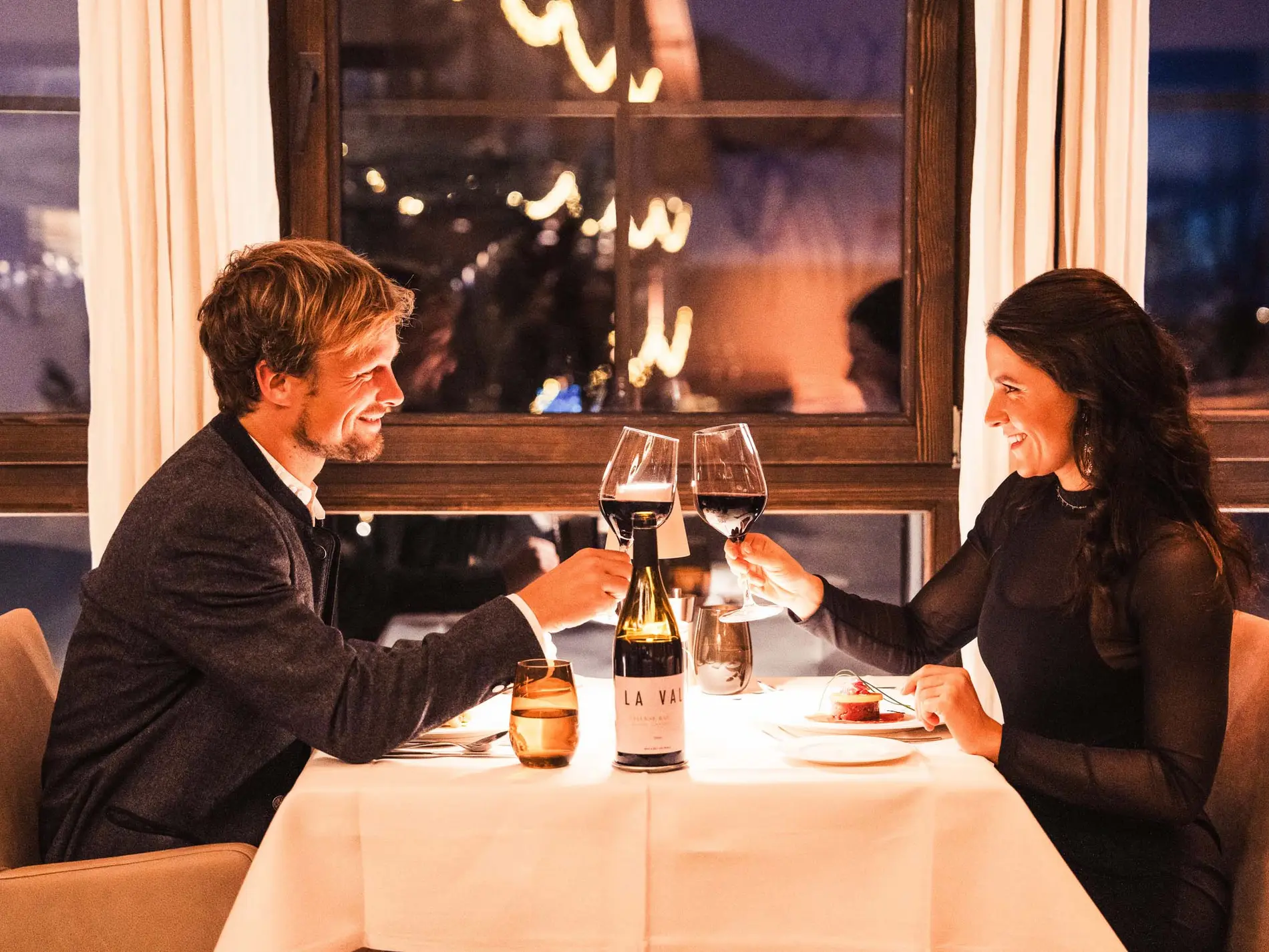 Kulinarische Vielfalt in unseren Restaurants in Brigels Paar stößt mit Wein in einem gemütlichen Restaurant an