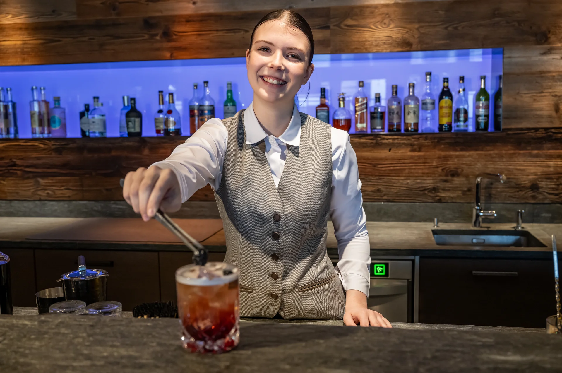 Lächelnde Barkeeperin serviert einen Cocktail an der Bar