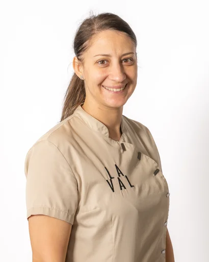 Porträt einer lächelnden Frau in beiger Arbeitskleidung vor weißem Hintergrund