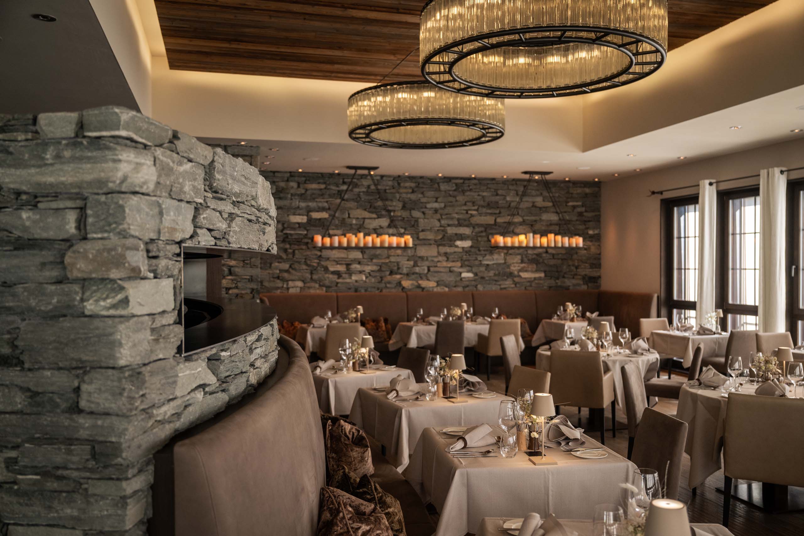 Elegantes Restaurant mit Kamin, Steinwand und gedeckten Tischen