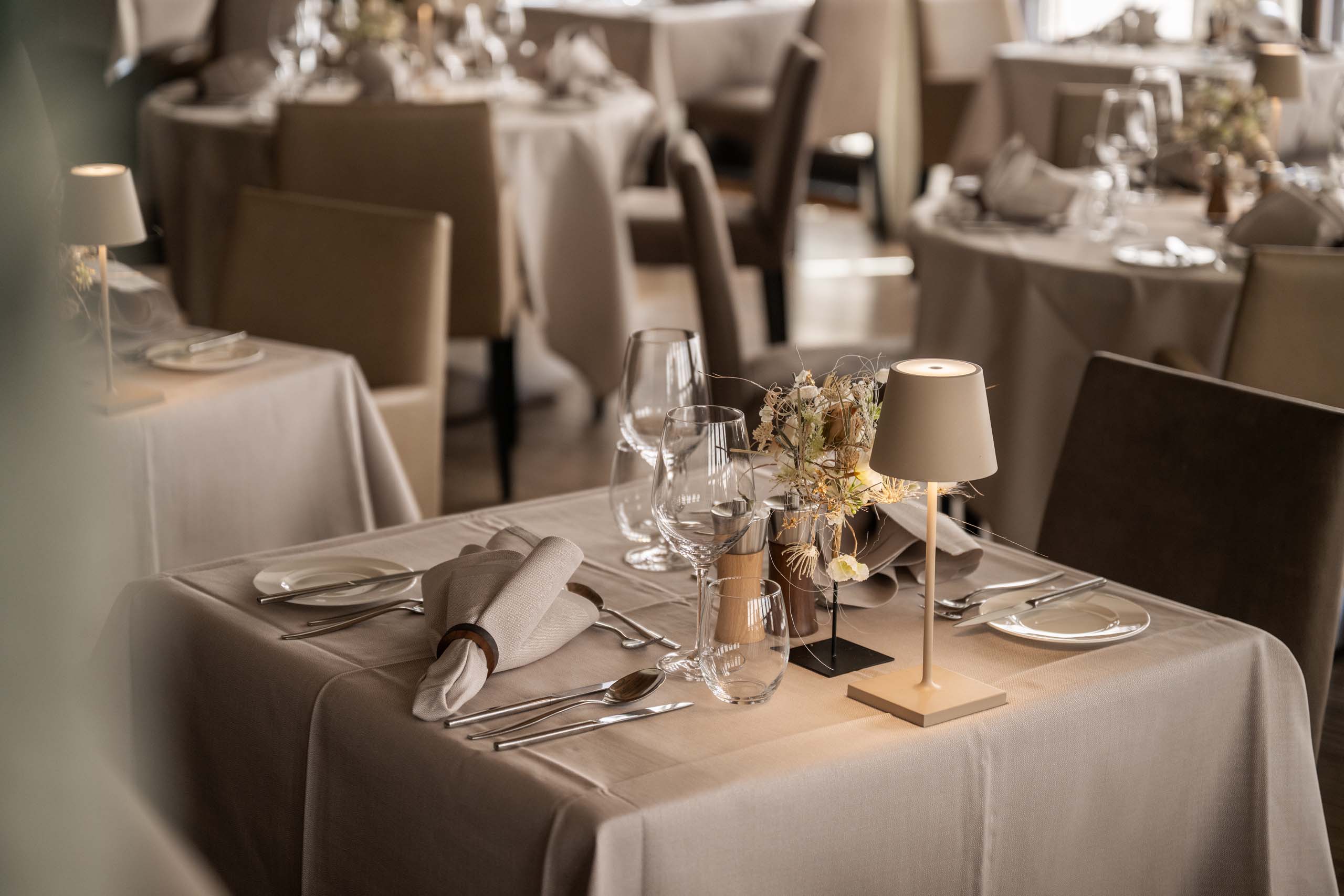 Eleganter Tisch in einem Restaurant mit weißer Tischdecke, Besteck und Lampe