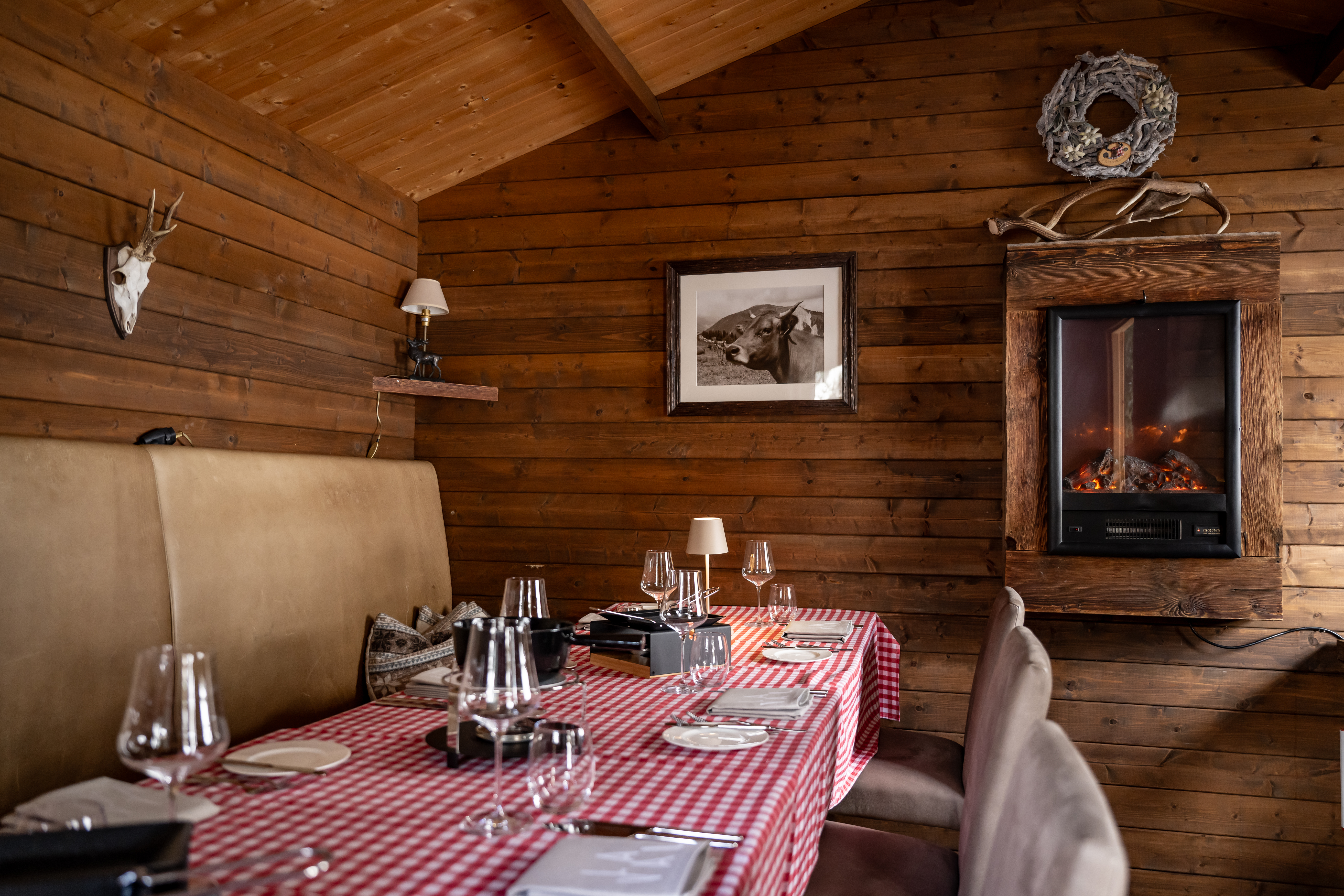 Gemütlicher Essbereich mit kariertem Tisch, Holzwänden und Wandofen