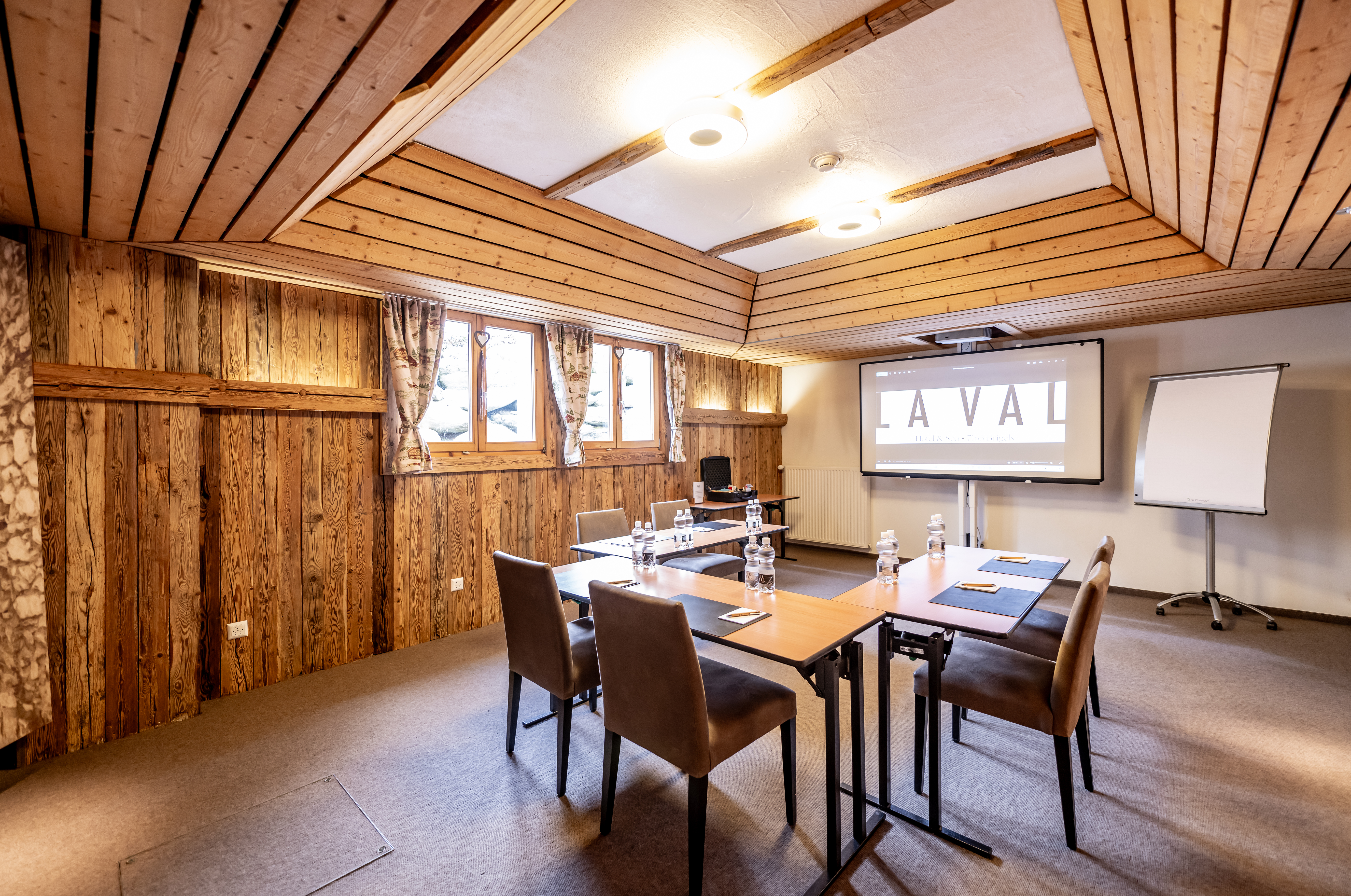 Konferenzraum mit Holzwänden, Stühlen, Tischen und Projektor
